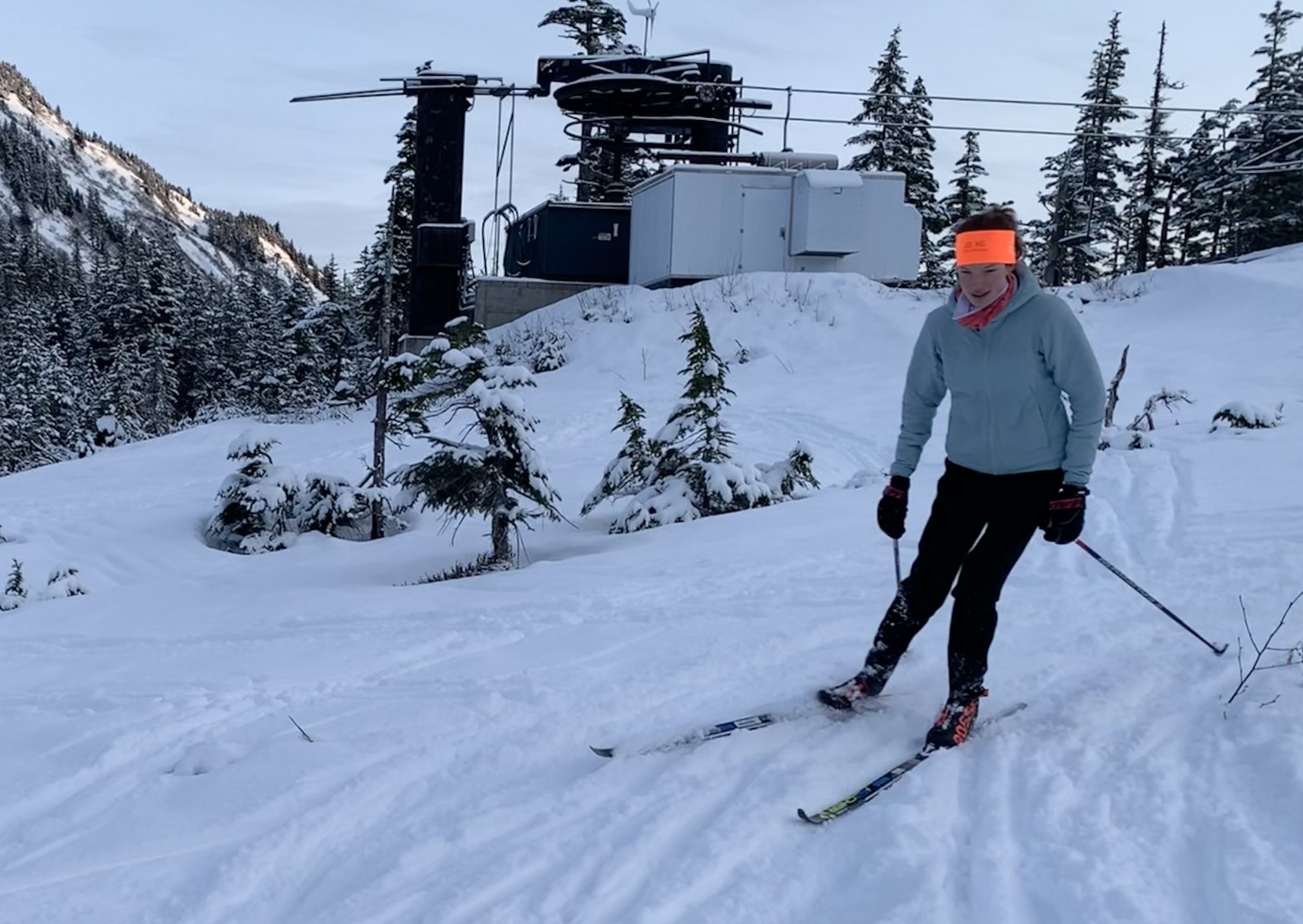 girl with red hair and orange bandana skis down a snowy slope