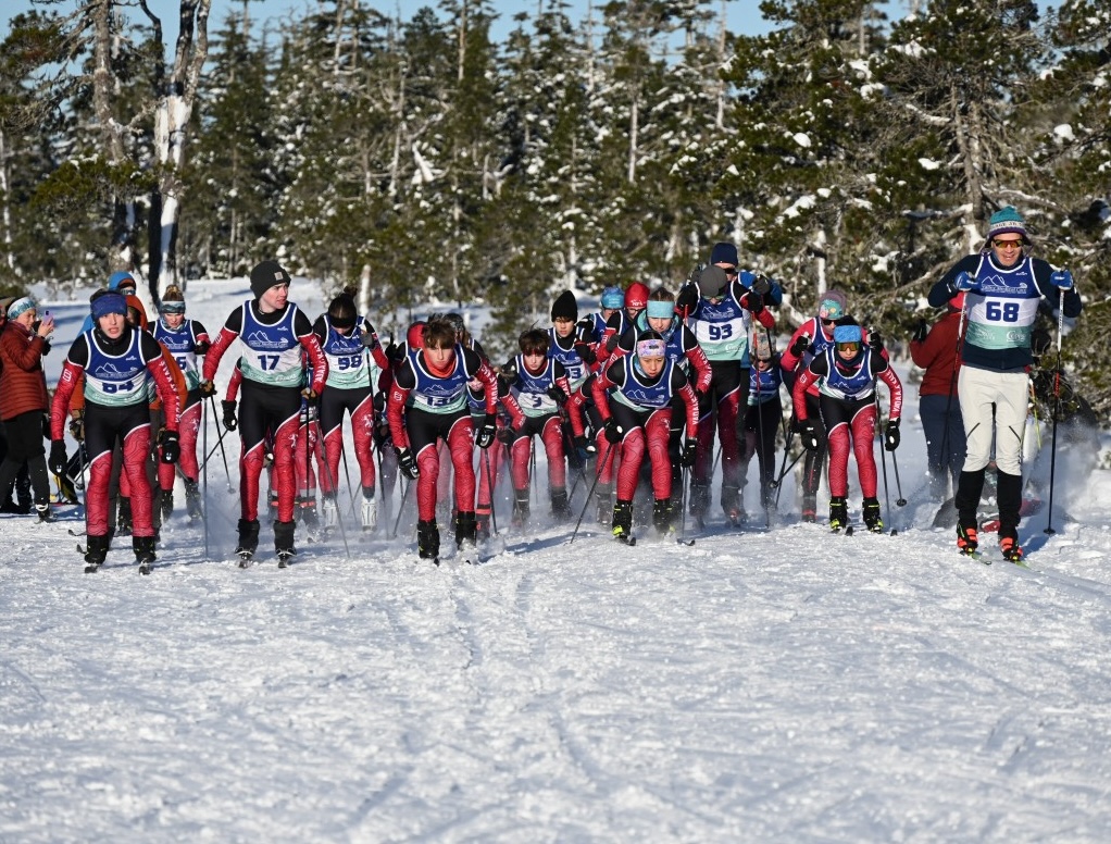 Juneau-Douglas Yadaa.at Kalé Ski Team-All photos-66412434231 (1) a young female ski race in an orange, light blue and gray race suit skate skis down a hill